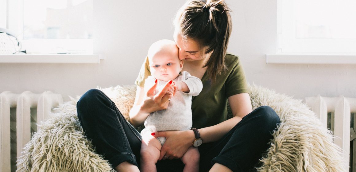 woman-holding-baby-while-sitting-on-fur-bean-bag-698878